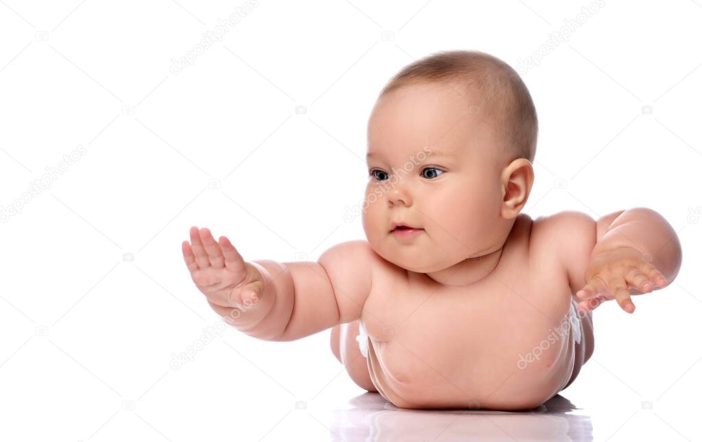Infant child baby girl kid in diaper is lying on her tummy, stomach holding hands up, slapping on floor 