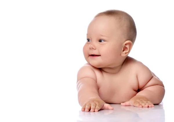 Leende, fnissande spädbarn baby flicka unge i blöja ligger på magen håller armen utsträckt tittar åt sidan — Stockfoto
