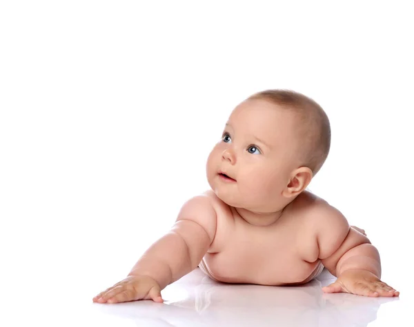 Niño curioso bebé bebé niña en pañal está acostada sobre su barriga sosteniendo el brazo extendido y mirando a la esquina superior — Foto de Stock