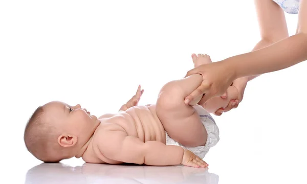 Niño bebé niña en pañal está acostada sobre su espalda haciendo ejercicios para fortalecer las piernas y los músculos de la espalda. Vista lateral —  Fotos de Stock