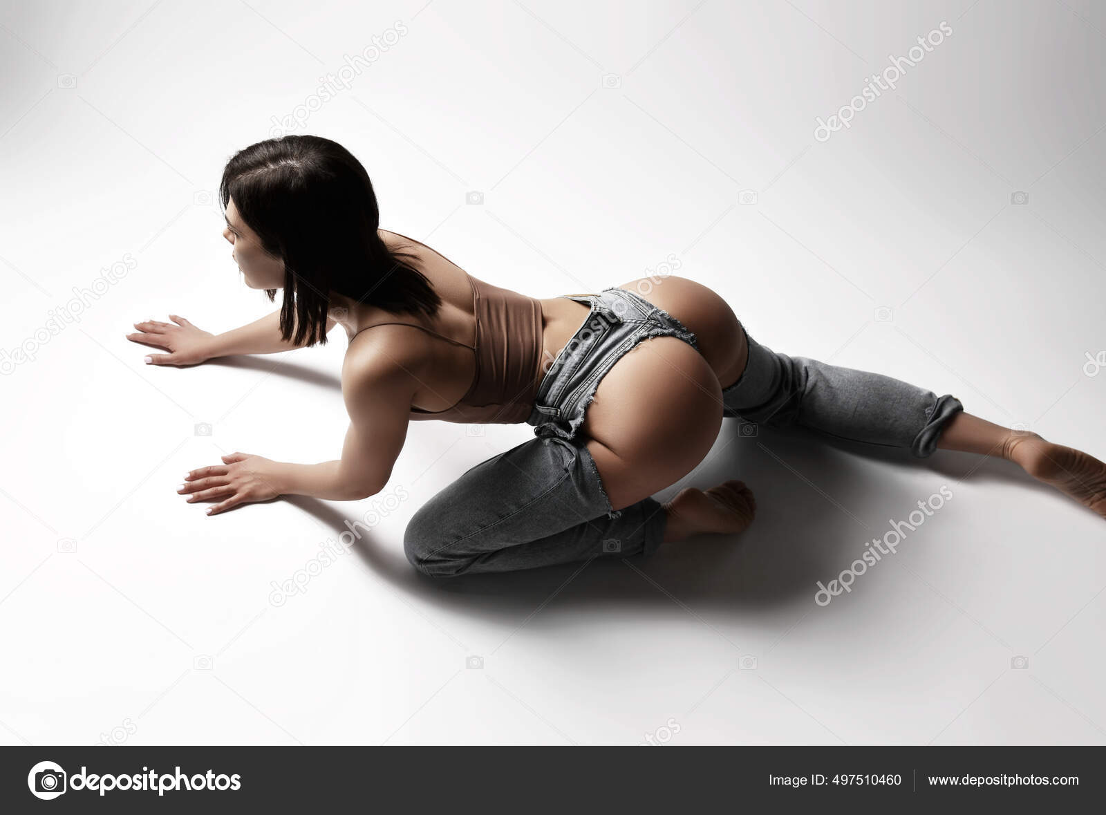 Top view of beautiful young brunette woman in damaged grey jeans with naked booty and top lying on white floor Stock Photo by ©dml5050 497510460