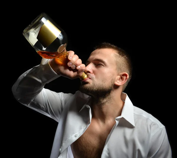 Hombre bebiendo whisky con alcohol de coñac de la botella —  Fotos de Stock