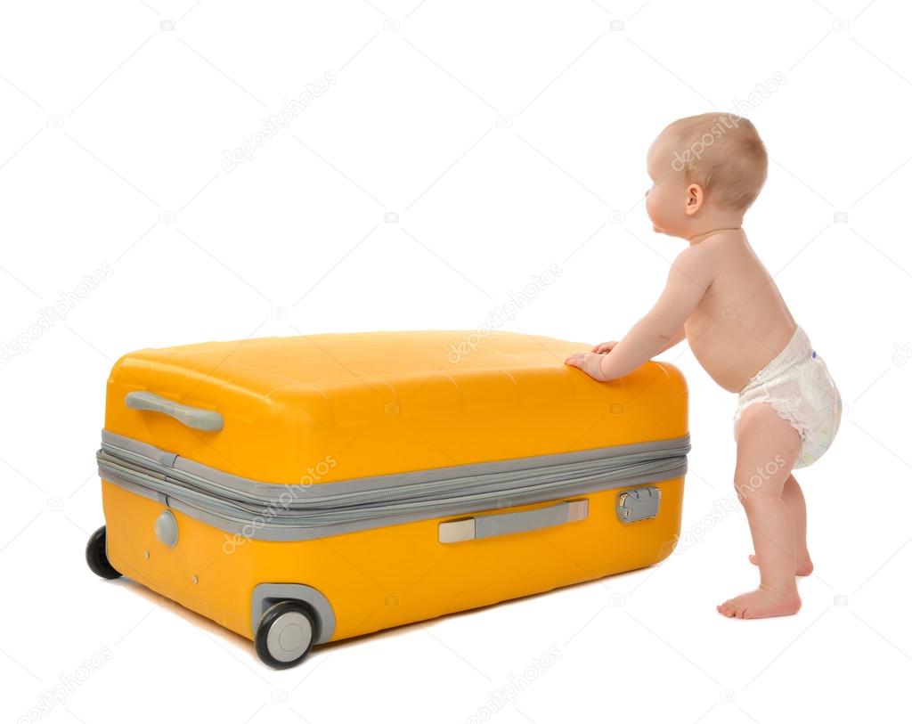 Happy infant baby toddler sitting in yellow plastic travel suitc