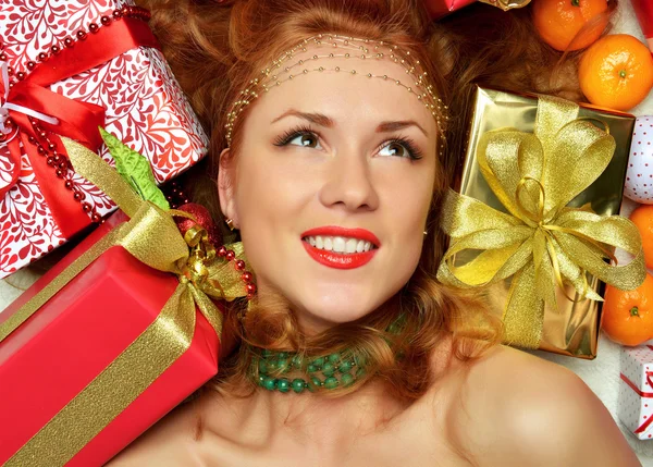 Glückliche junge Frau hält rotes weihnachtlich verpacktes Geschenk-Smilin in der Hand — Stockfoto