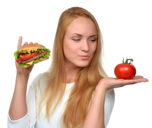 Vrouw vergelijken smakelijke ongezonde burger broodje in de hand en toma — Stockfoto