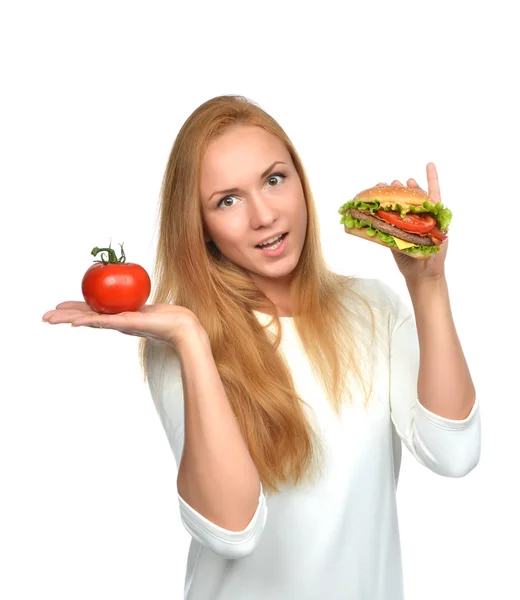 Woman comparing tasty unhealthy burger sandwich in hand and toma — Stock Photo, Image