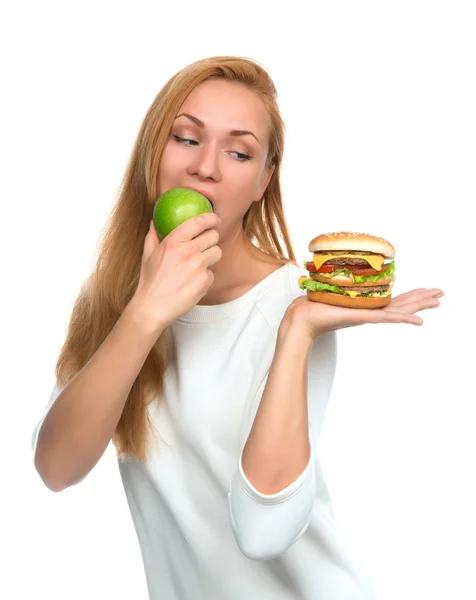 Woman comparing burger sandwich in hand and green apple — Stock Photo, Image