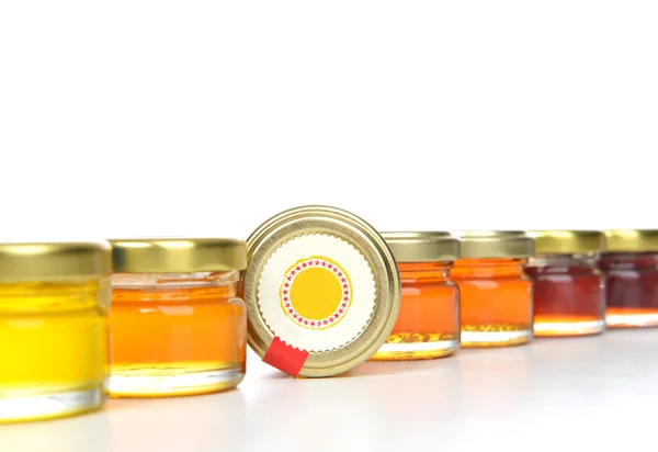 Tasty jars of jam and honey in a row — Stock Photo, Image
