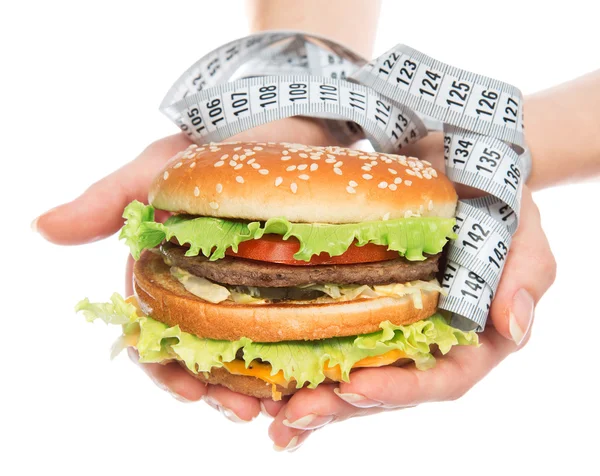 Fast food burger cheeseburger in hands with measure tape — Stock fotografie
