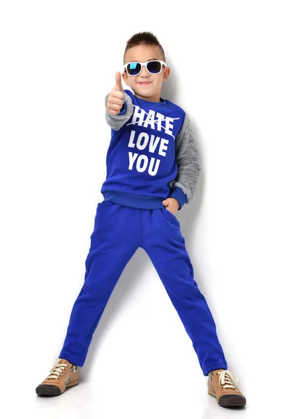 Little boy in sunglasses blue cloth jeans standing and giving th — Stockfoto