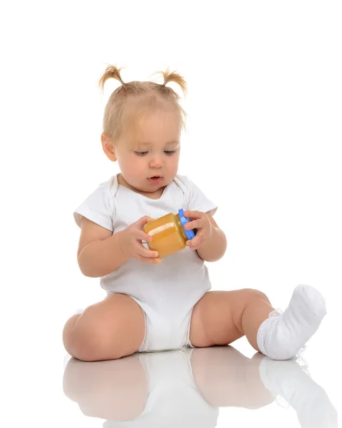 Infant Baby girl kid sitting and holdingin hands jar of child ma — Stock Photo, Image