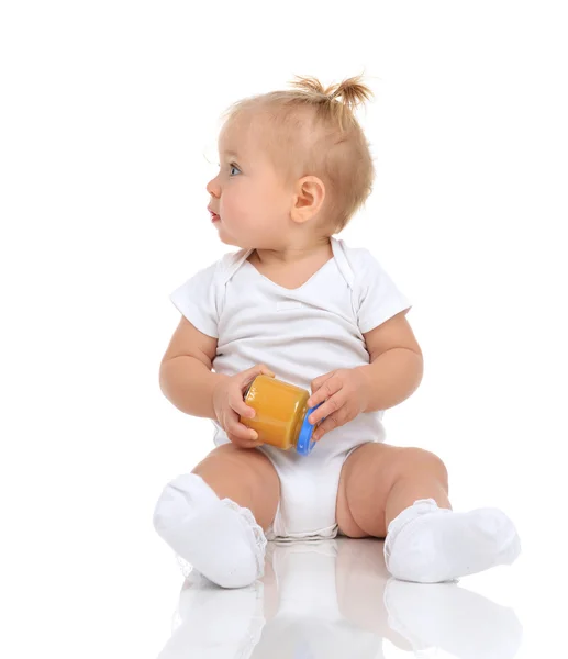 Baby girl sitting and holding jar of child mash puree food — Stok fotoğraf