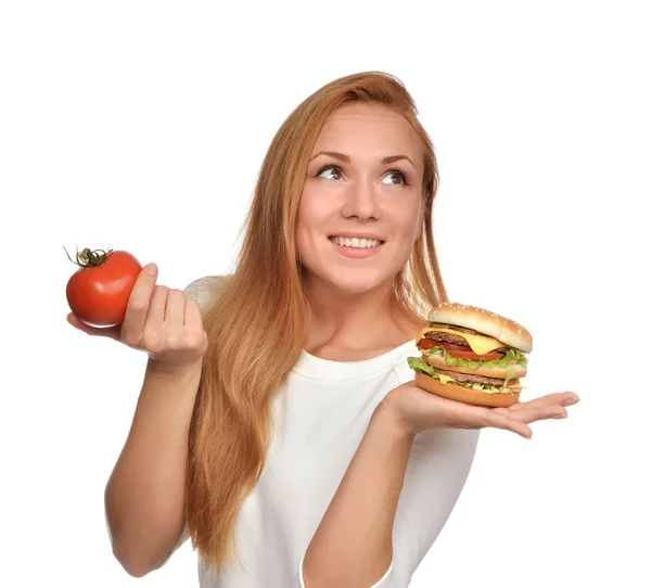 Woman comparing tasty unhealthy burger sandwich in hand and toma — Stock Photo, Image