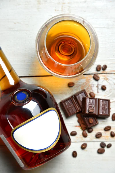 Glass of brandy cognac on a old wooden table with chocolate coff — Stock Photo, Image