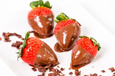 Çikolata batırılmış çilek, çikolata parçaları onun etrafında.