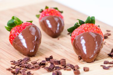 Çikolata batırılmış çilek, çikolata parçaları onun etrafında.