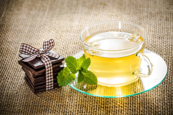 Tazza di tè in vetro foglie di menta e cioccolato . Fotografia Stock