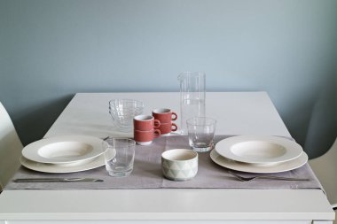 Ön planda modern bir yemek odasının iç çekimleri. Yemek masası bulaşıklarla dolu.