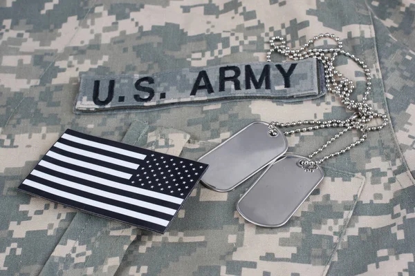 US flag patch with dog tags on camouflage Army Combat Uniform background