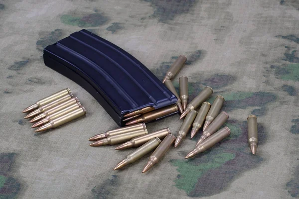 5.56mm ammunition with full metal jacket bullet with magazine on camouflage uniform background