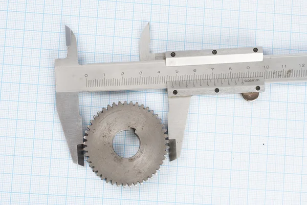 Gear and caliper on  graph paper — Stok fotoğraf