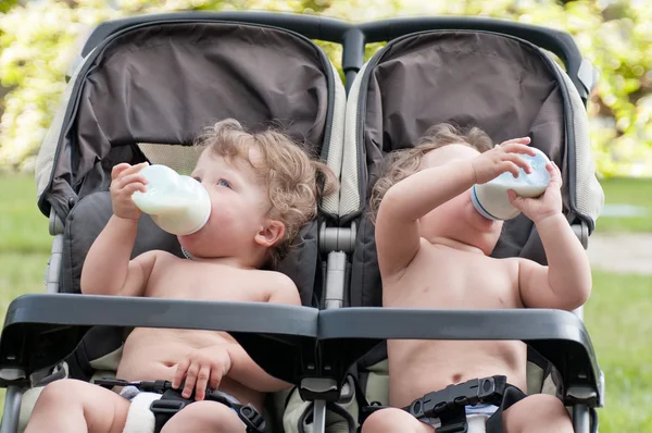 Twins suck bottle with milk — Stock Photo, Image