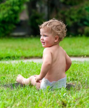 küçük çocuk yeşil çimenlerin üzerinde oturuyor