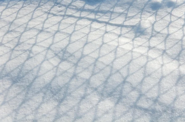 Stíny na sněhu z kovové mřížky — Stock fotografie