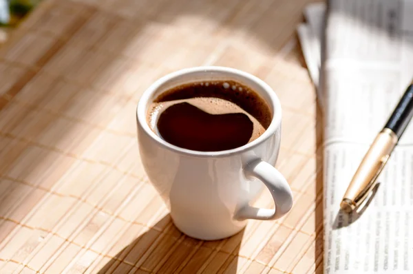 Kopp svart kaffe, tidning och en penna — Stockfoto