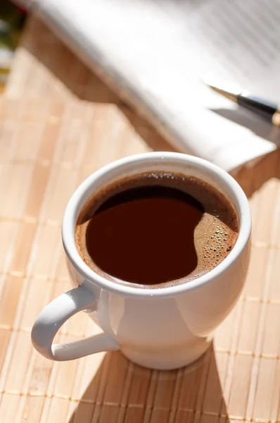 Cup of black coffee, newspaper and a pen — Stock Photo, Image