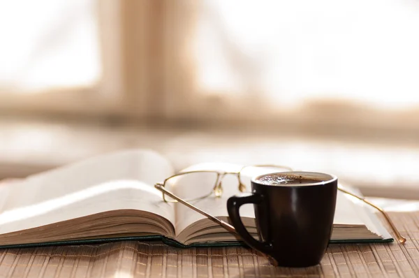 Cup of coffee with open book and glasses — Stock Photo, Image