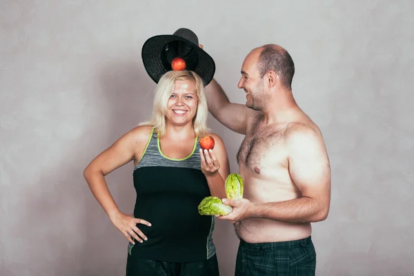 Vrolijke corpulente paar met groenten en fruit — Stockfoto