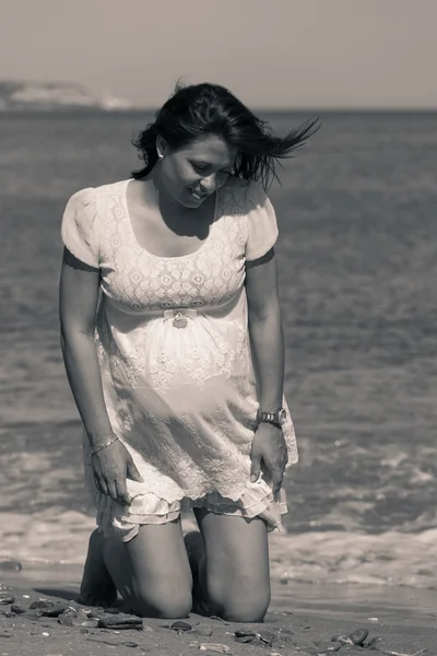Ganska gravid kvinna på knä ner på stranden — Stockfoto