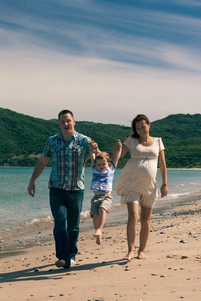 Feliz familia saltando y caminando por la costa en España —  Fotos de Stock