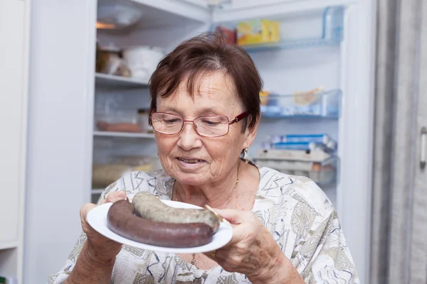 Mulher sênior feliz segurando prato com salsichas de fígado de porco — Fotografia de Stock