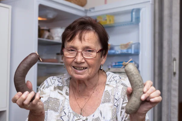 Happy senior woman holding pork liver sausages — Stock Photo, Image