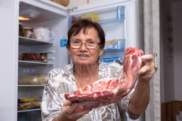 生の豚肉の肋骨を持つ幸せな年配の女性 — ストック写真