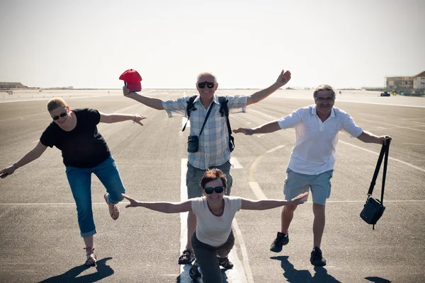 Lustige Menschen imitieren Flugzeug auf der Landebahn des Flughafens — Stockfoto