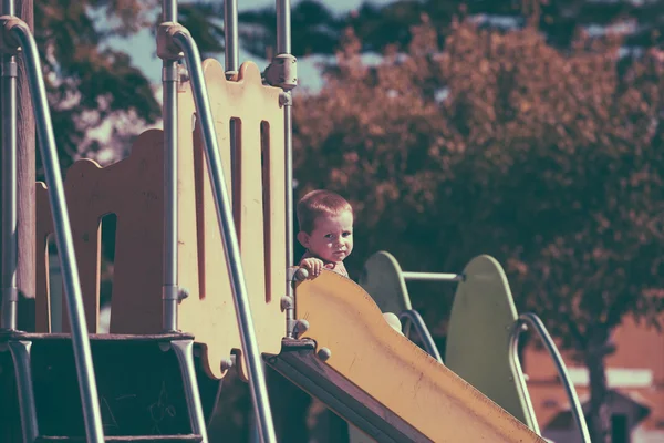 Vintage photo of child boy on slide at playground Stock Photo