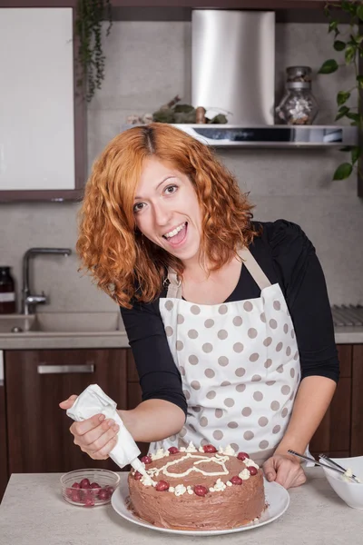 Excited woman decorating cake at home — Stock Photo, Image