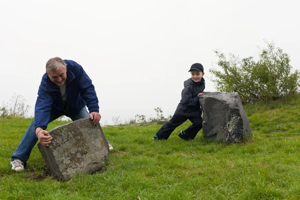 Senior and child moving big boulder — Stock Photo, Image