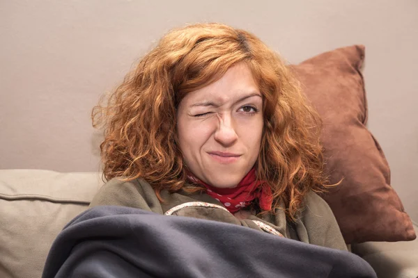 Redhead woman with one eye closed relaxing on sofa — Stock Image Redhead woman with one eye closed relaxing on sofa Stock Image