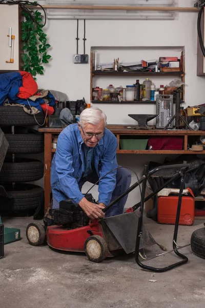 Seniorin mit Rasenmäher in Werkstatt Stockfoto