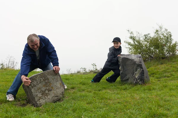 Senior und Kind bewegen große Felsbrocken Stockfoto