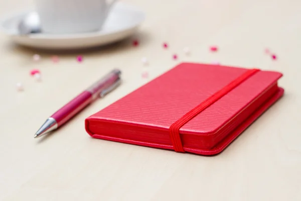 Red notebook with pen and coffee on wooden — Stock Photo, Image