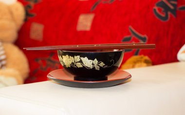 Üzerinde kırmızı ve siyah Japon yemek çubukları kase