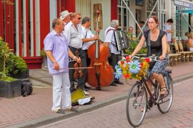 Girl cyclist with flowers and street musicians (Buskers) near ca clipart