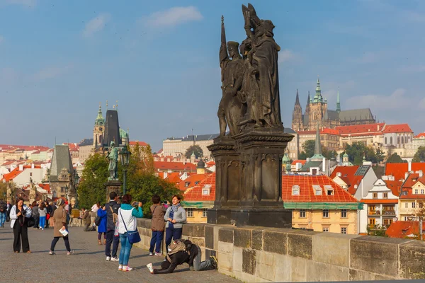 Beggar and tourists on the Charles Bridge in Prague — Stock Photo, Image