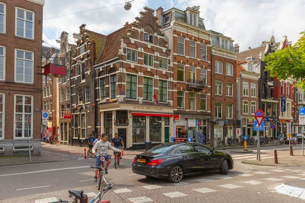 Rowerzystów i samochód na skrzyżowaniu typowe w Amsterdamie — Zdjęcie stockowe