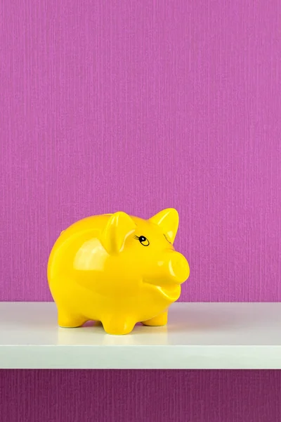 A happy yellow piggy bank on a shelf — Stock Photo, Image